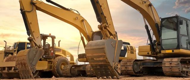 Heavy construction equipment and excavators at sunset on building site