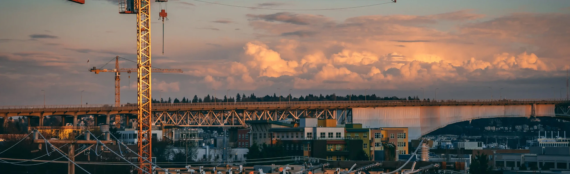 Construction cranes at sunset over industrial site - services banner desktop